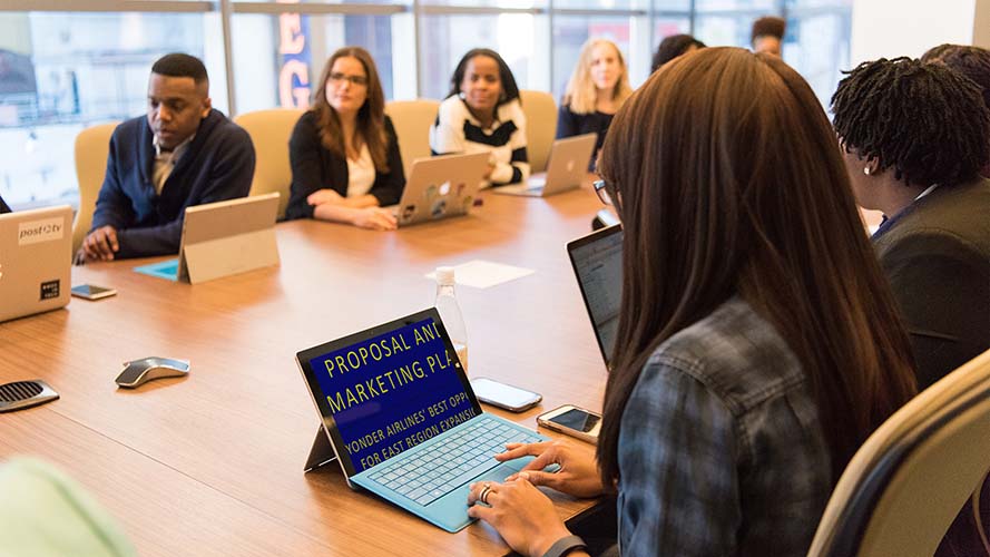 Office worker in a boardroom meeting viewing the presentation on a laptop.